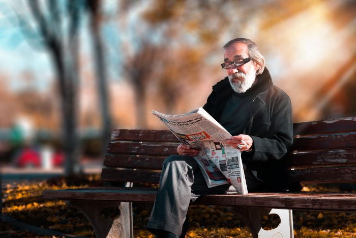 man reading newspaper in park