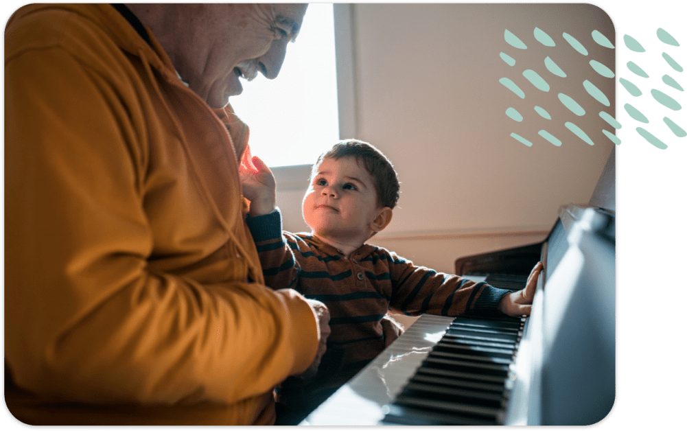 Senior man with young child sitting at the piano together