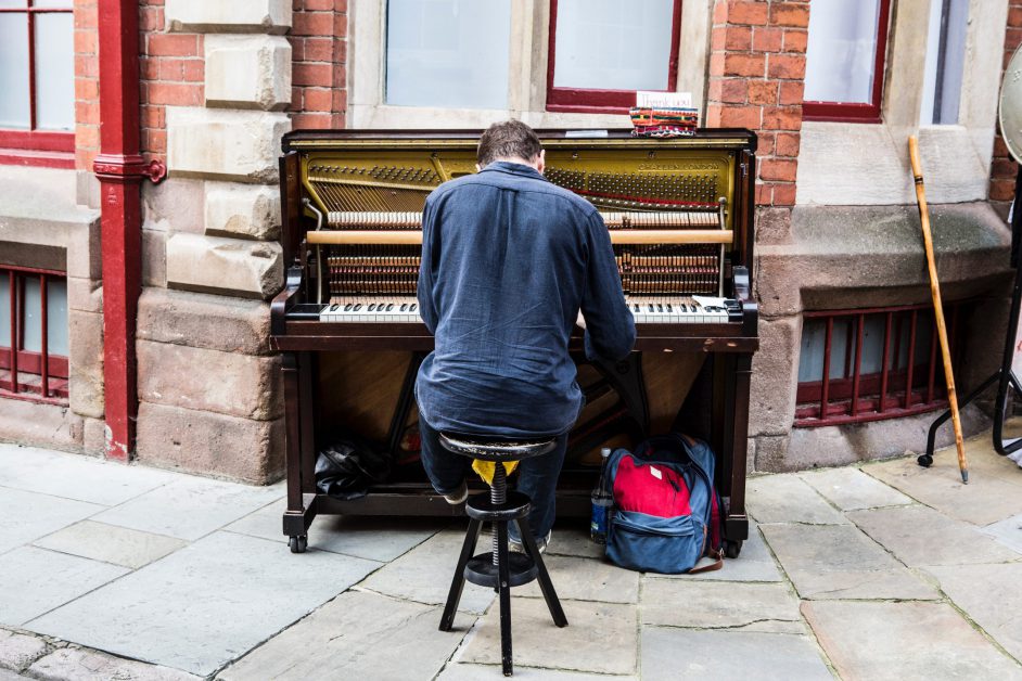 man sitting at piano on sidewalk