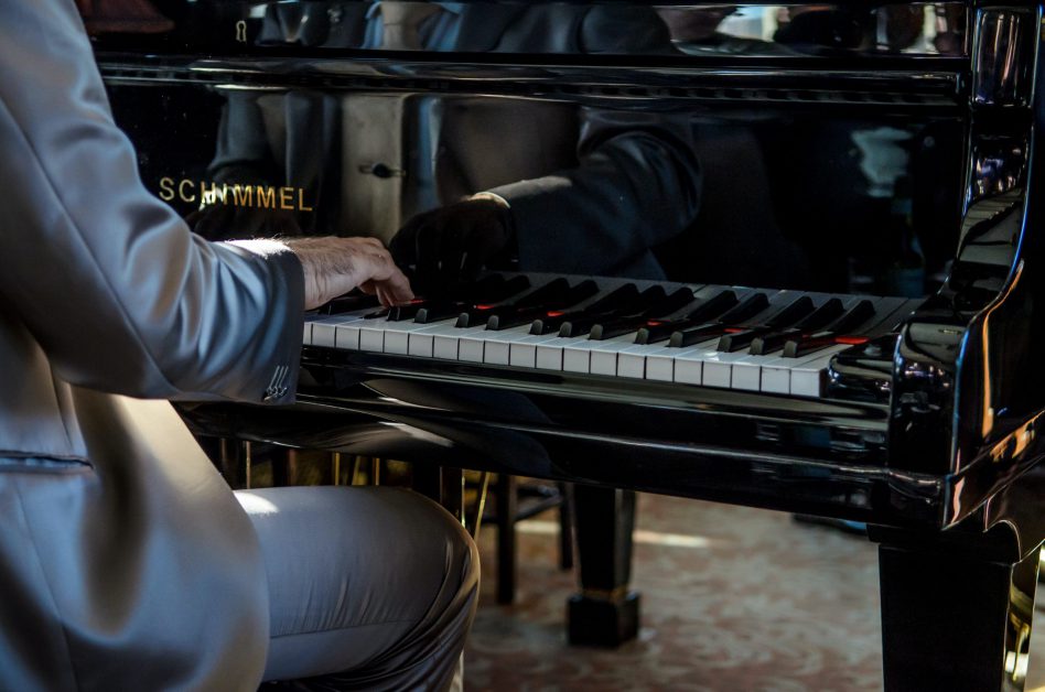 man in suit playing piano outside