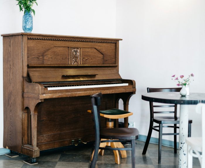 brown upright piano by wall